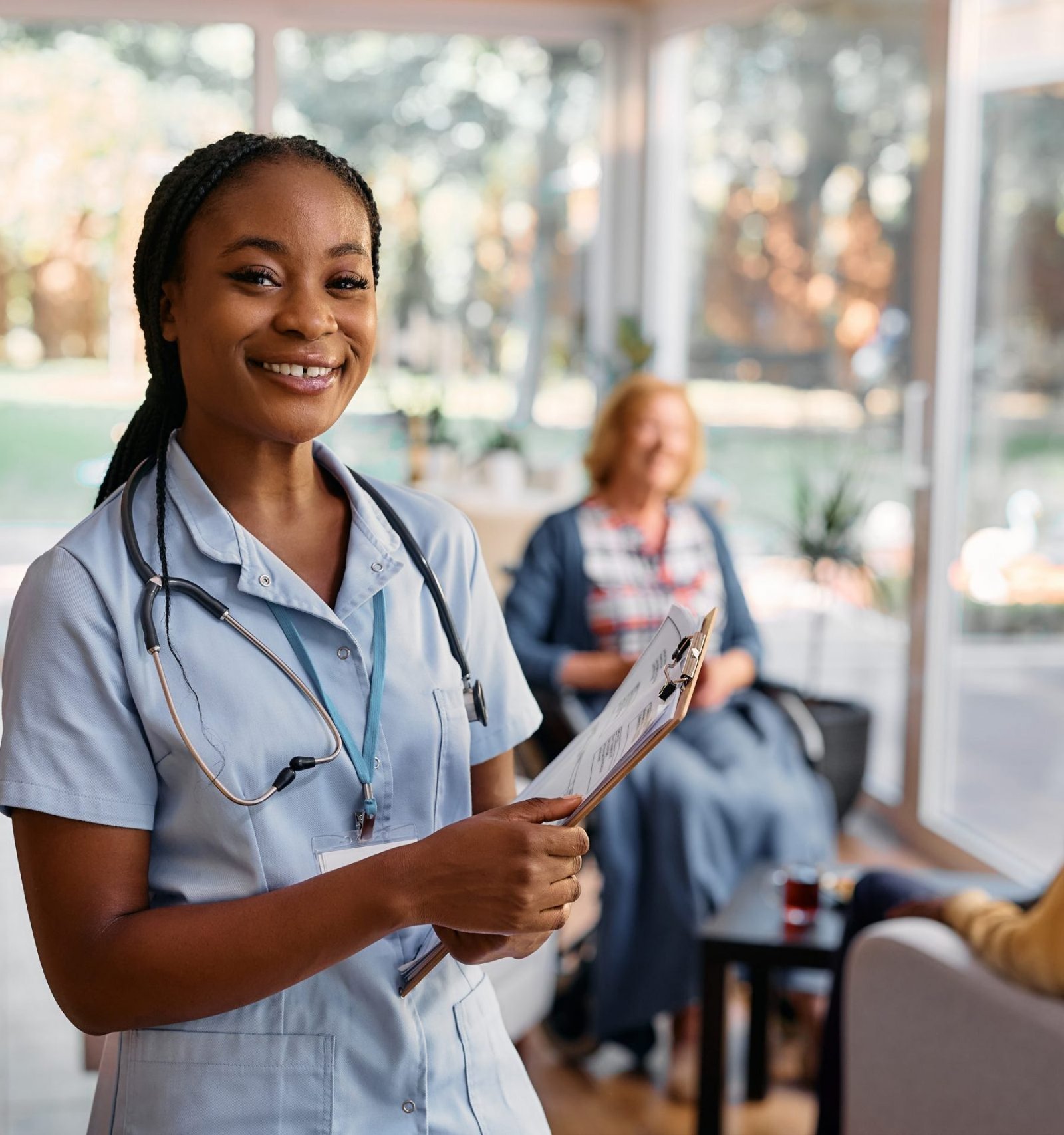 Happy African American caregiver working at nursing home and looking at camera.